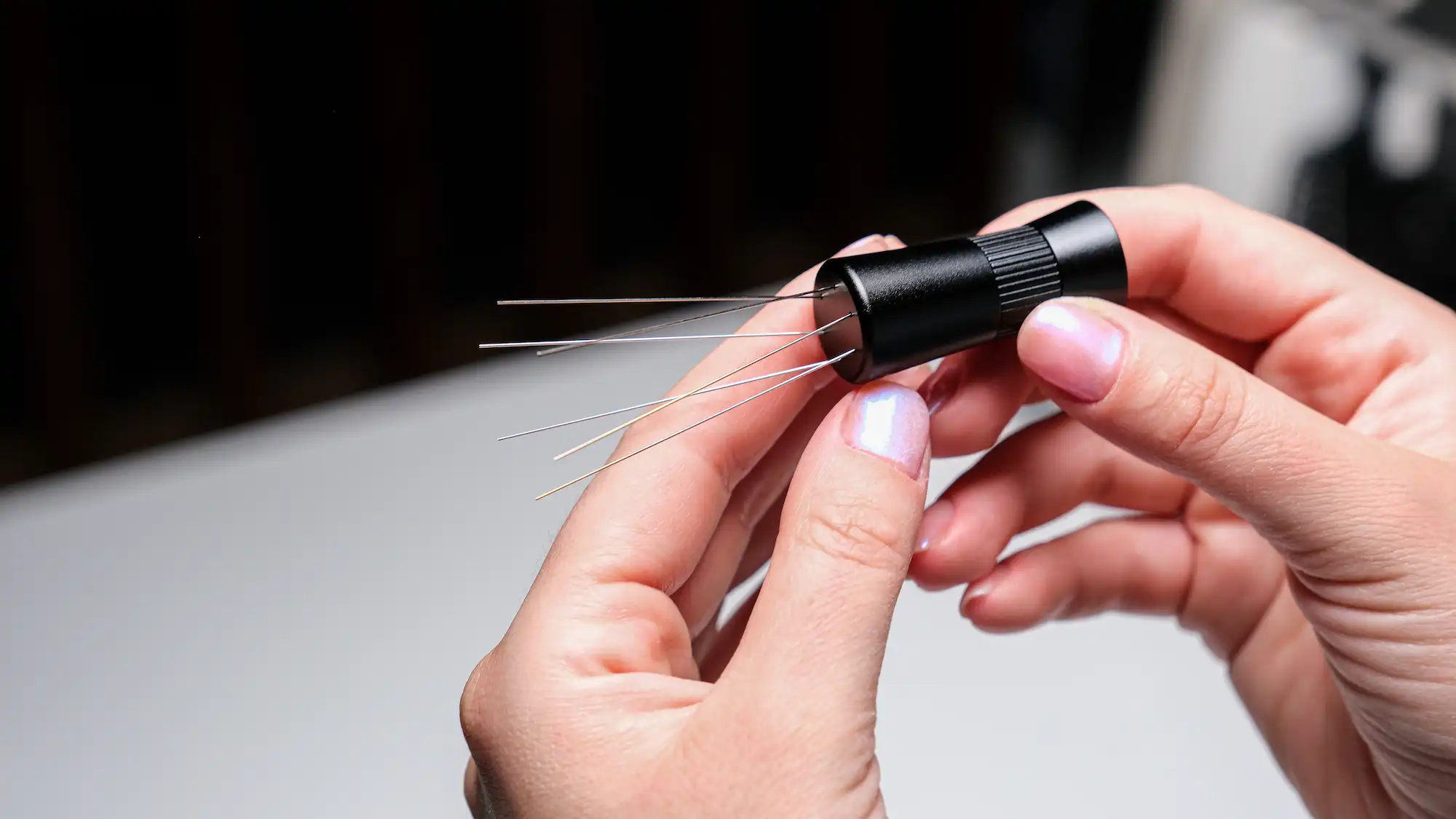 Hands holding a KNODOS WDT tool, showing the fine distribution needles up close